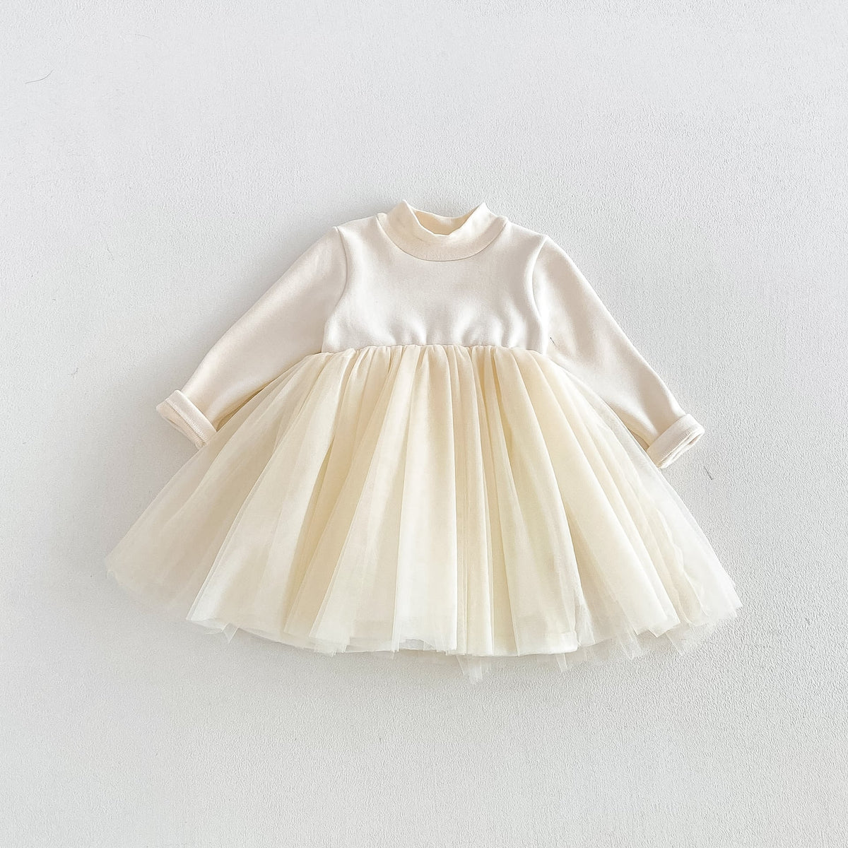 Cream long-sleeve toddler dress with a layered tulle skirt, flat lay