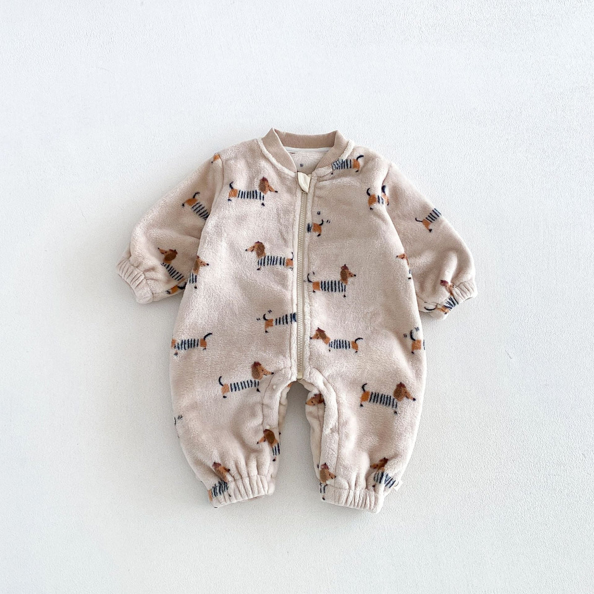 Oatmeal plush fleece baby romper with dachshund print and front zip, flat lay
