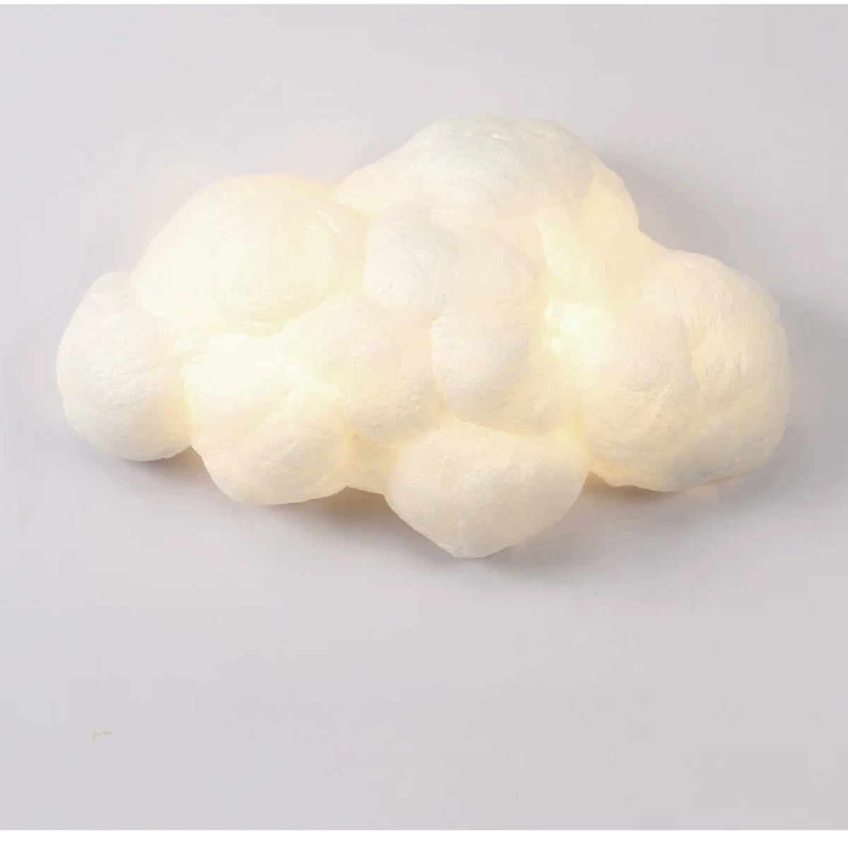 Glowing white cotton cloud wall lamp switched on against a pale wall