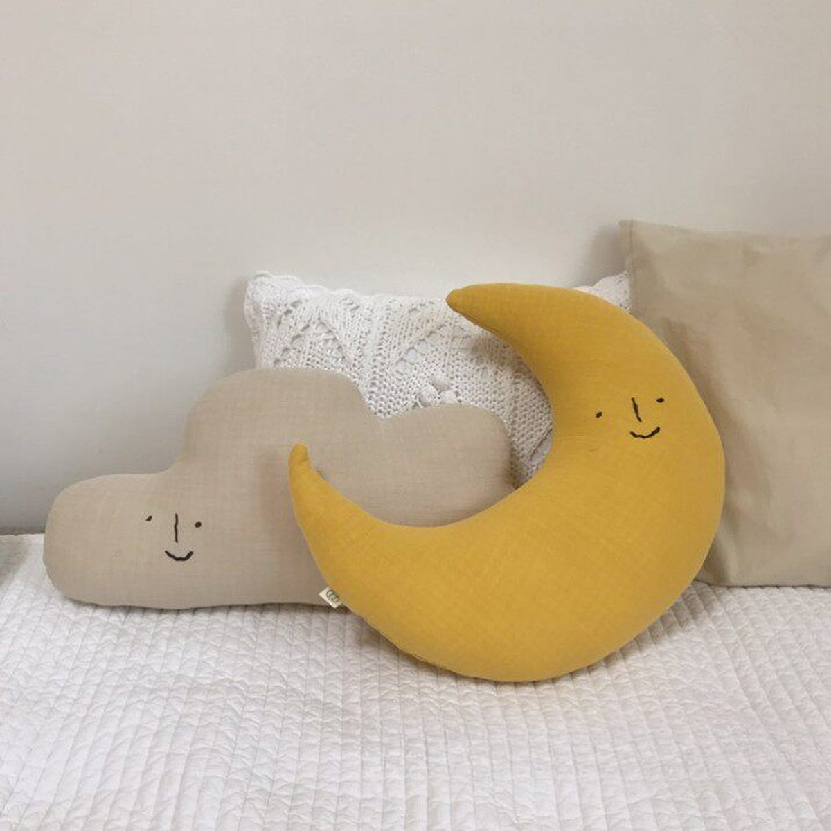 Cloud and yellow moon cushions on a white quilted bed