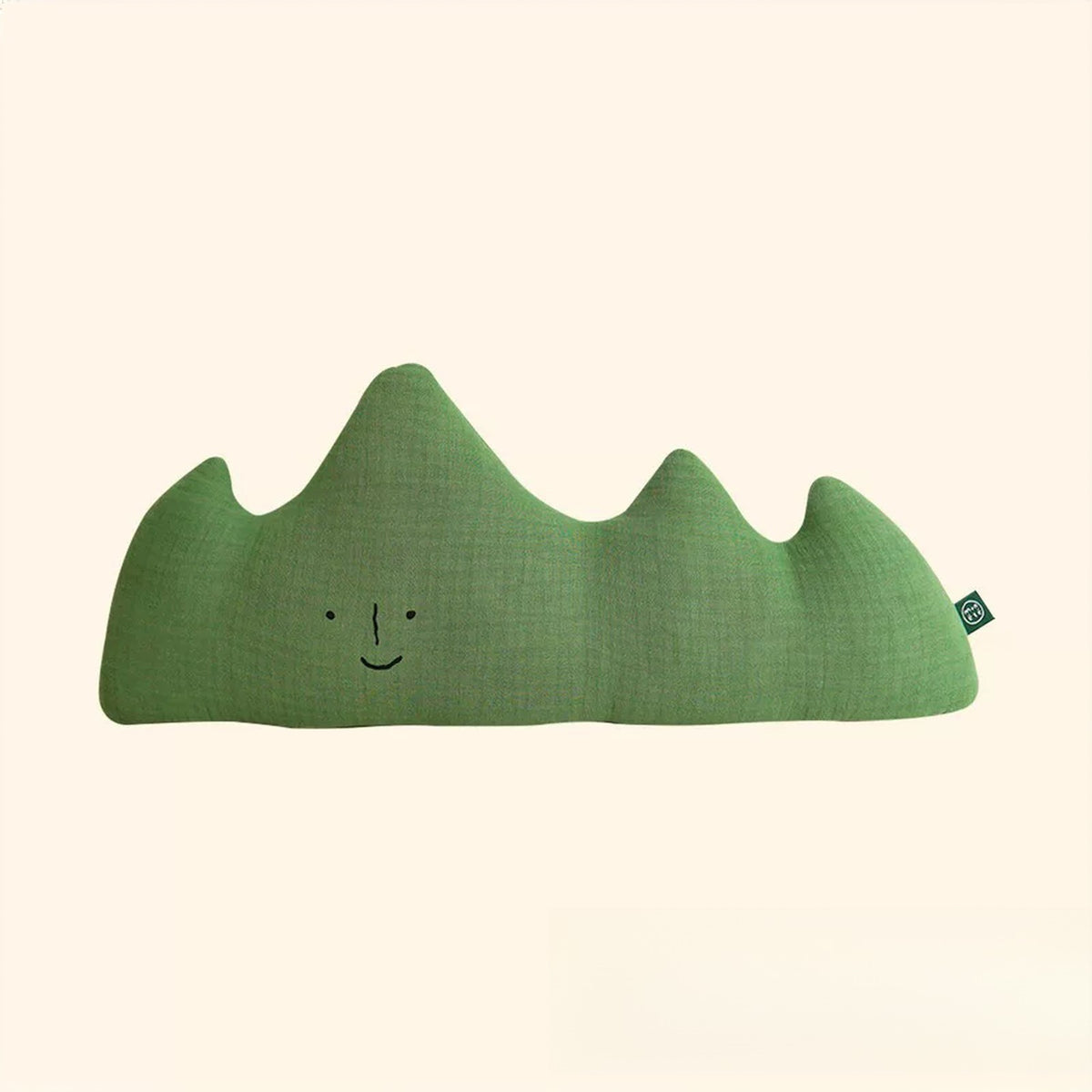Green mountain shaped muslin cushion with a smiling face