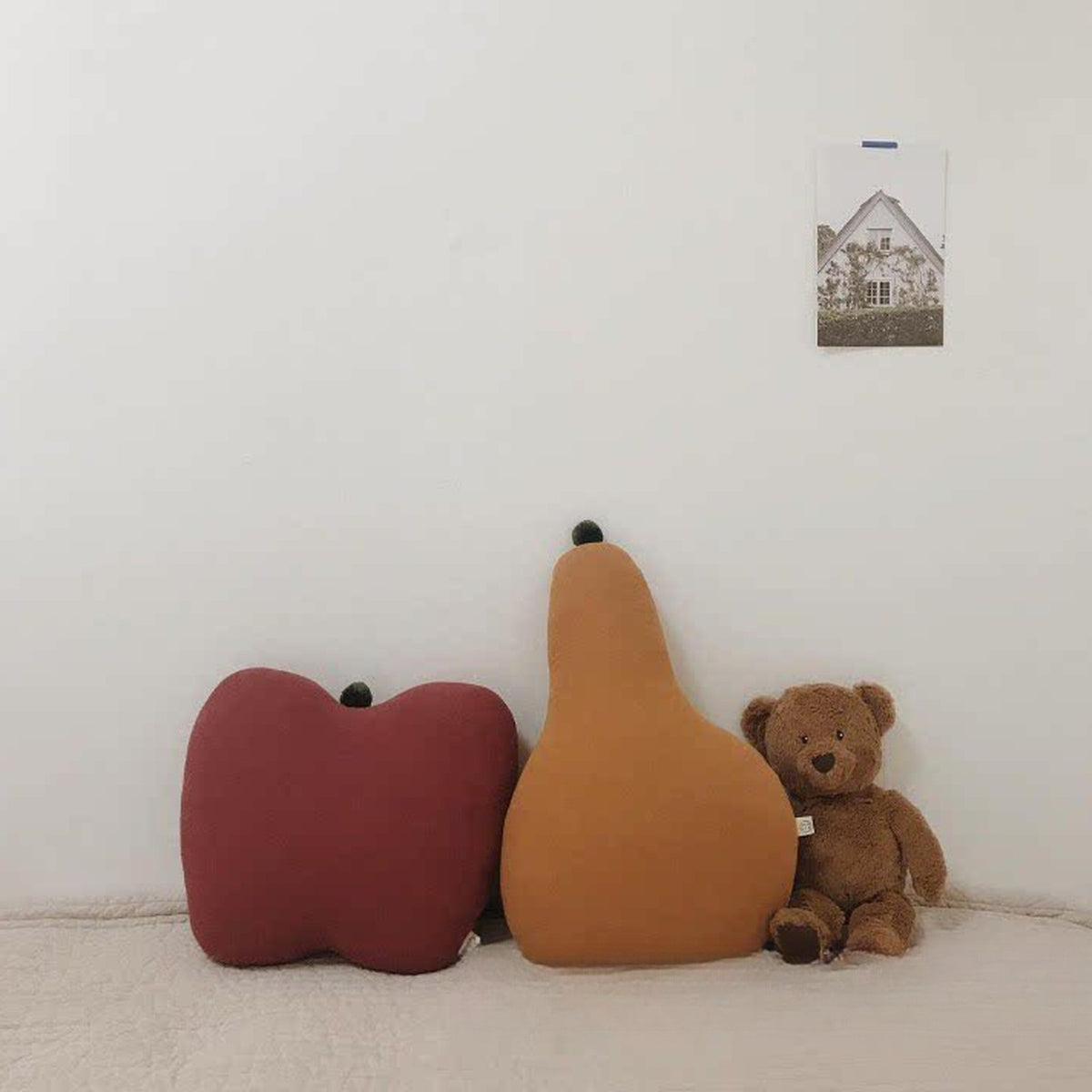 Red apple and pear cushions next to a teddy bear