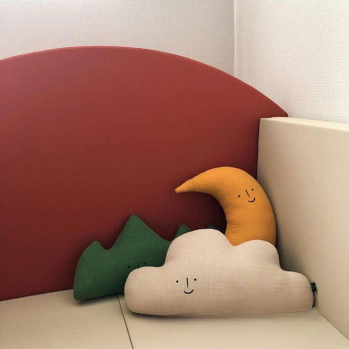 Mountain, cloud and moon cushions against a terracotta headboard