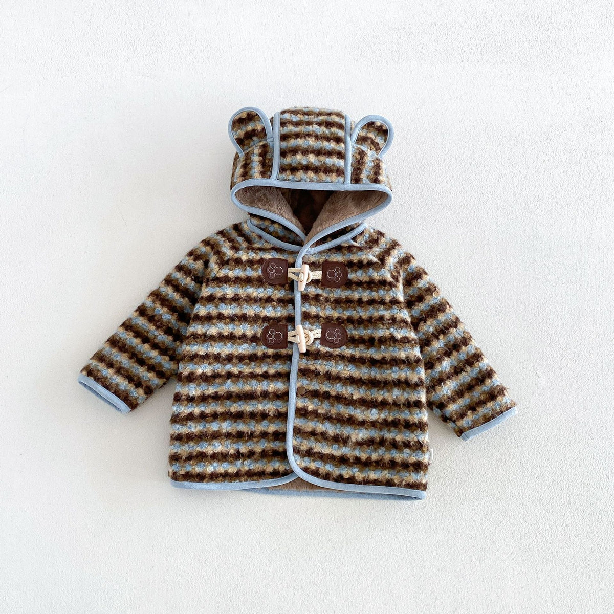 Brown and cream striped toddler duffle coat with sky blue trim and bear-ear hood, flat lay
