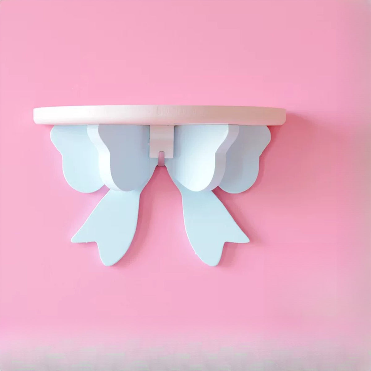 Cream shelf with a pale blue bow on a pink wall