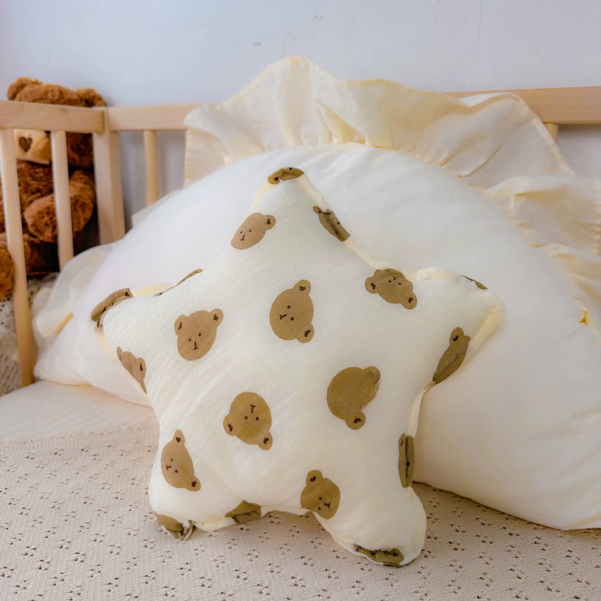 Little Bear print cream star cushion in a cot