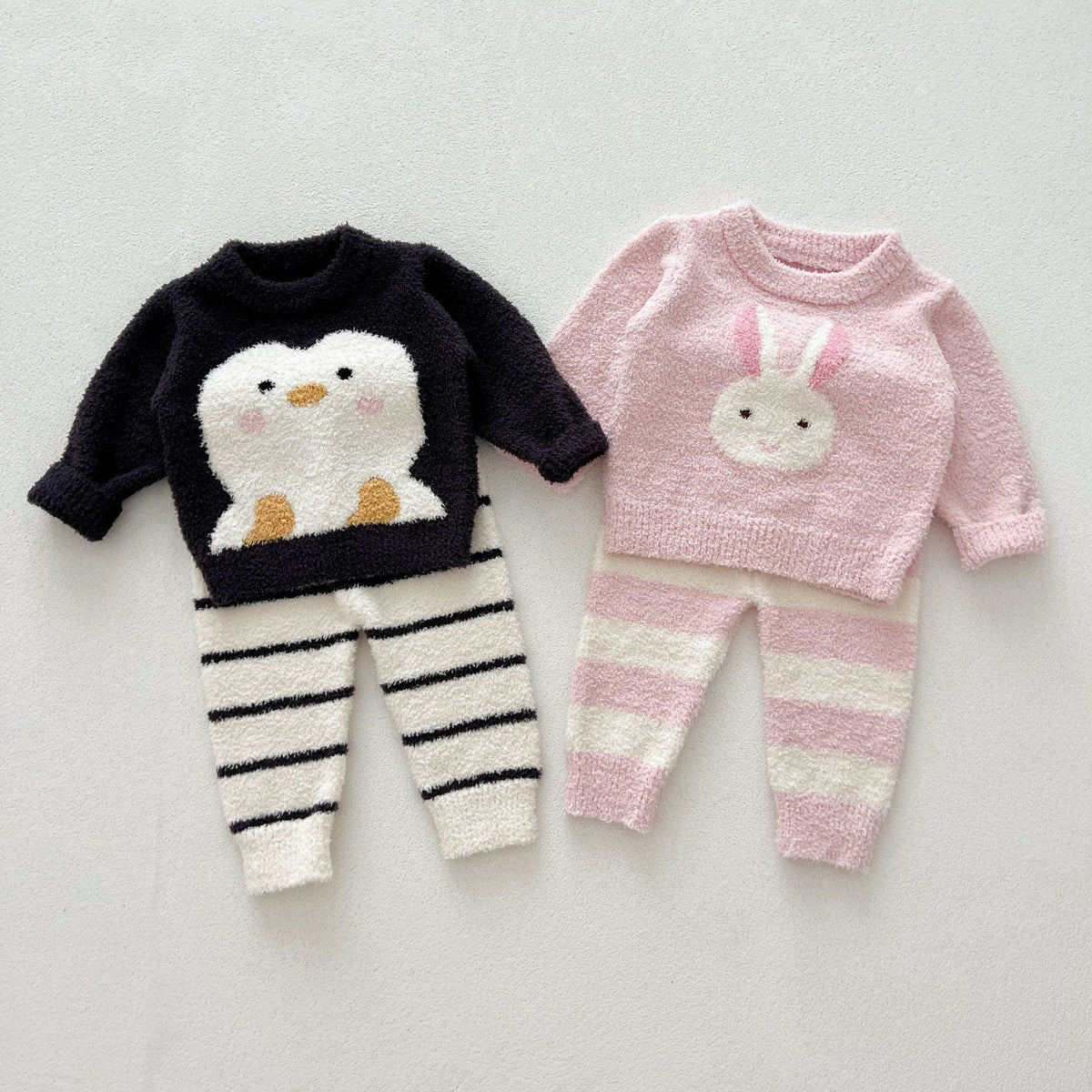 Penguin and bunny two-piece knit sets laid side by side