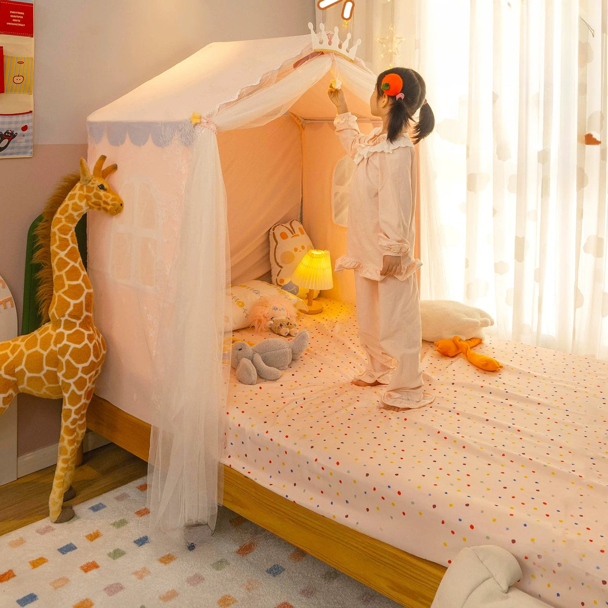 Princess cottage bed tent with crown and tied-back mesh curtain, child standing on the bed