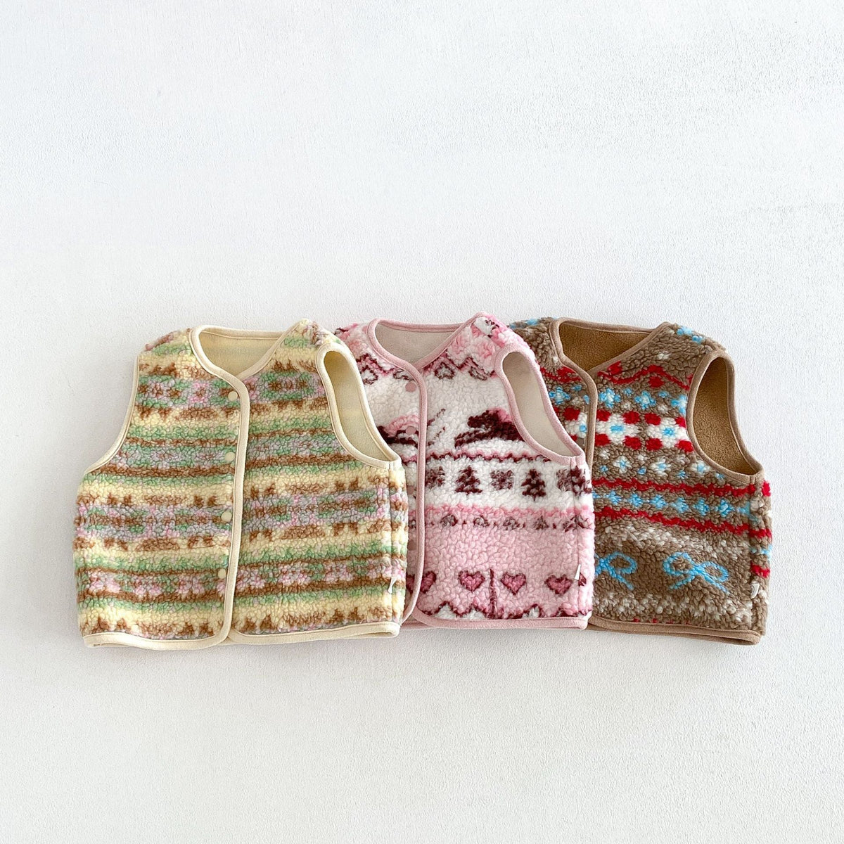 Three retro pattern fluffy fleece vests for kids in butter, pink and cocoa