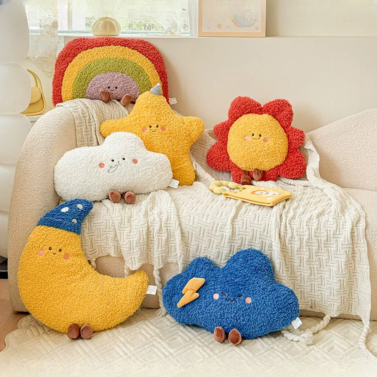 Moon, star, sun, rainbow, white cloud and storm cloud plush cushions on a cream sofa