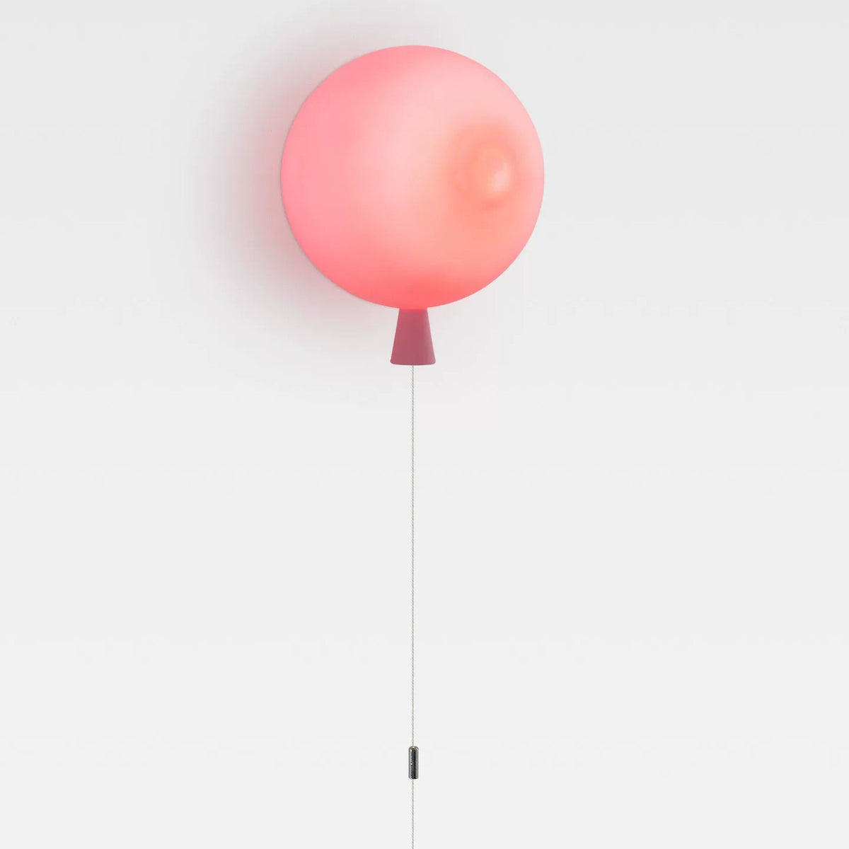 Frosted pink balloon wall lamp with pull cord on a white wall