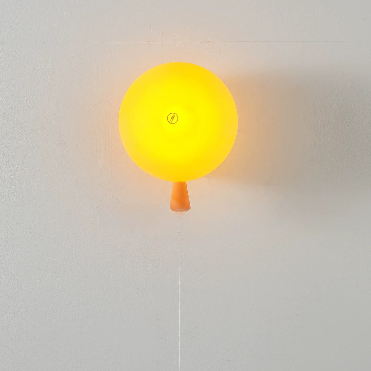 Orange balloon wall lamp lit with a warm glow