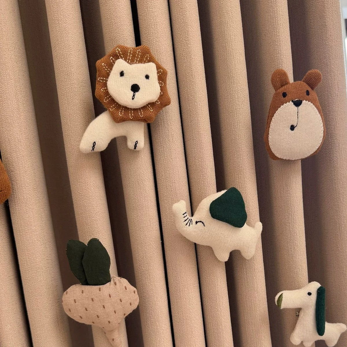 Close-up of handmade fabric lion, bear, elephant, radish and dog curtain pins