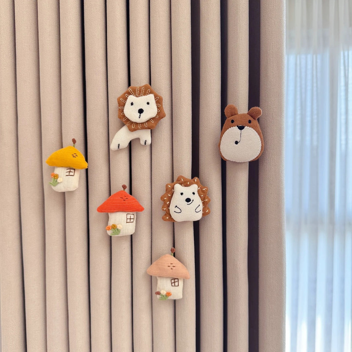 Little houses, lion, bear and hedgehog fabric pins on a curtain