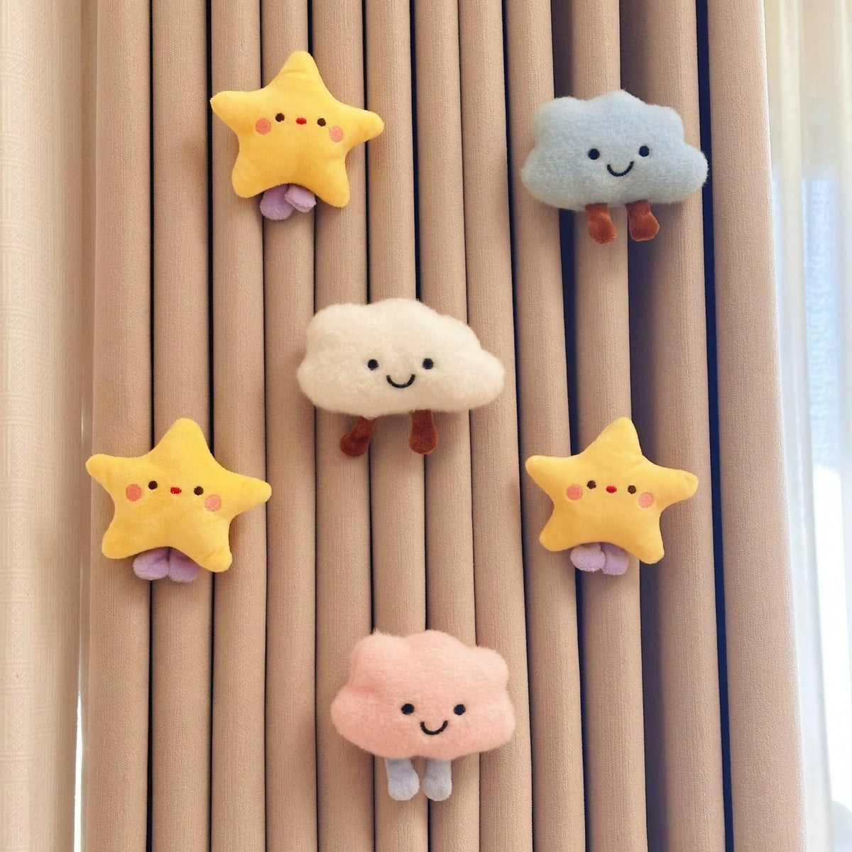 Plush cloud and star curtain charms pinned to beige curtains: white, blue and pink clouds with three stars
