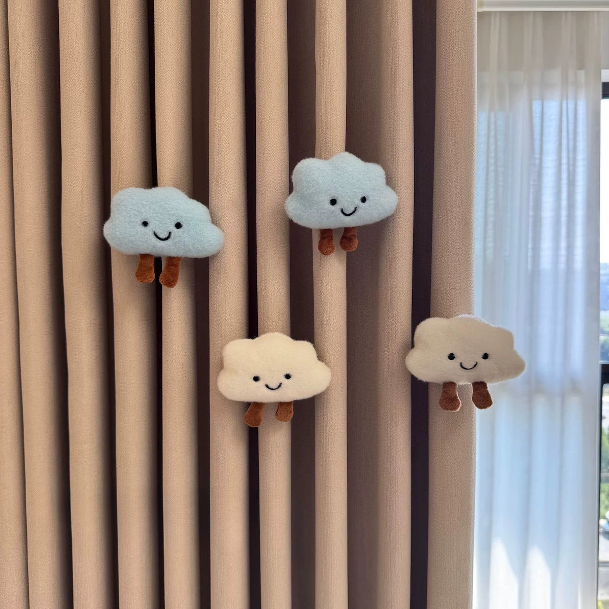 Two white and two blue plush cloud charms on a curtain