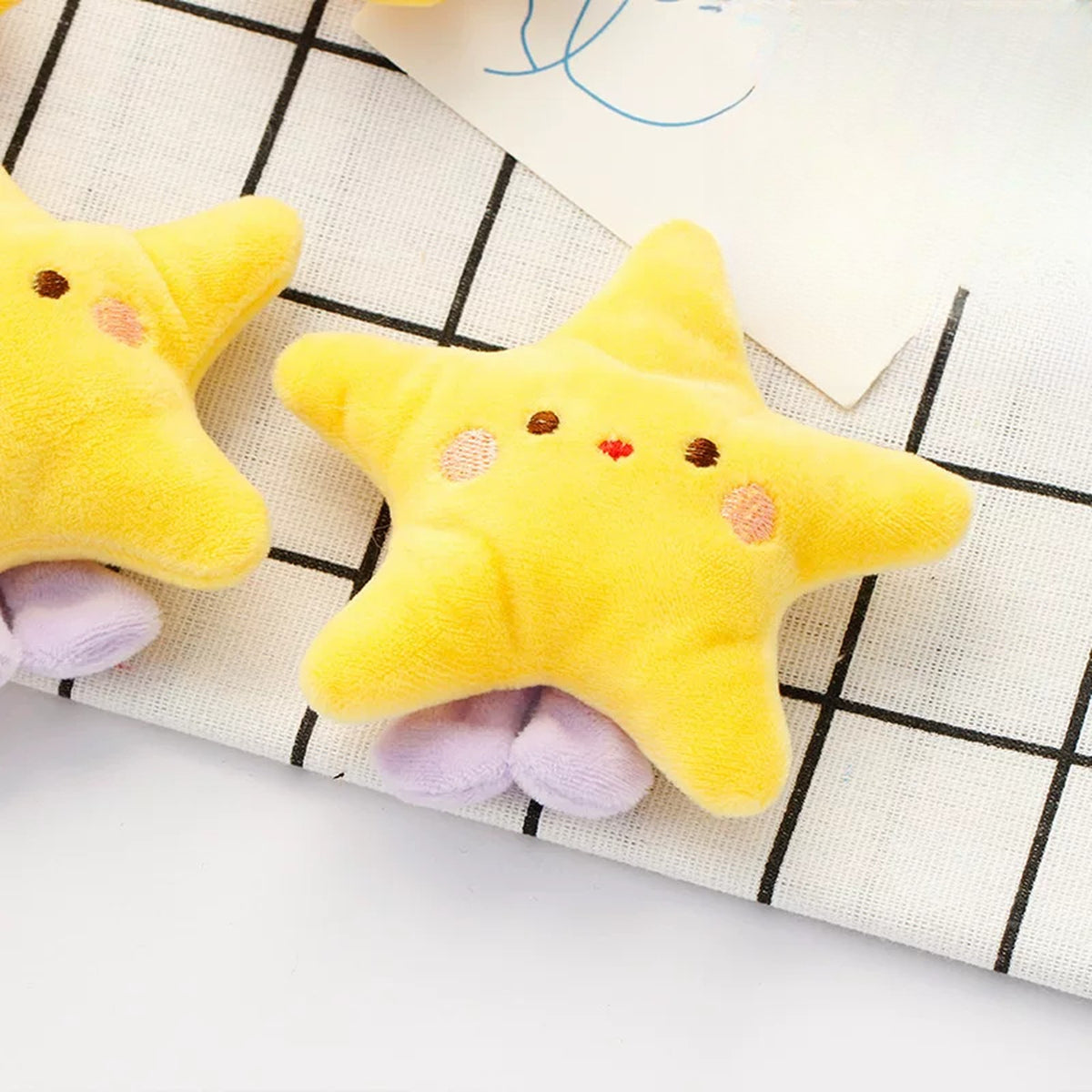 Close-up of a fluffy yellow plush star charm with little purple feet