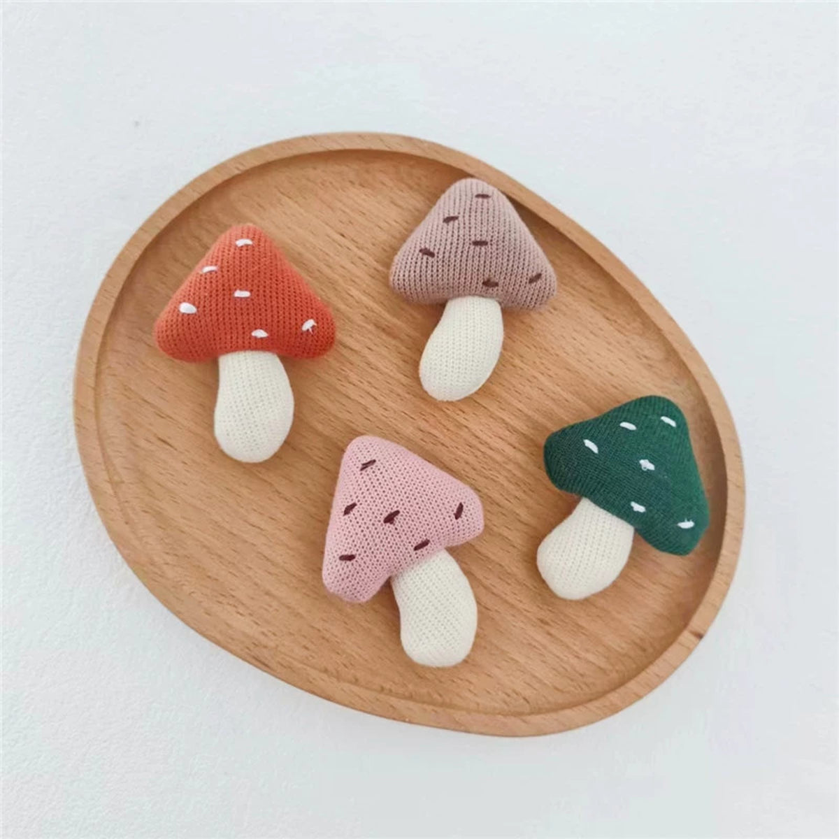 Little Mushrooms set of four knitted mushroom charms on a wooden tray