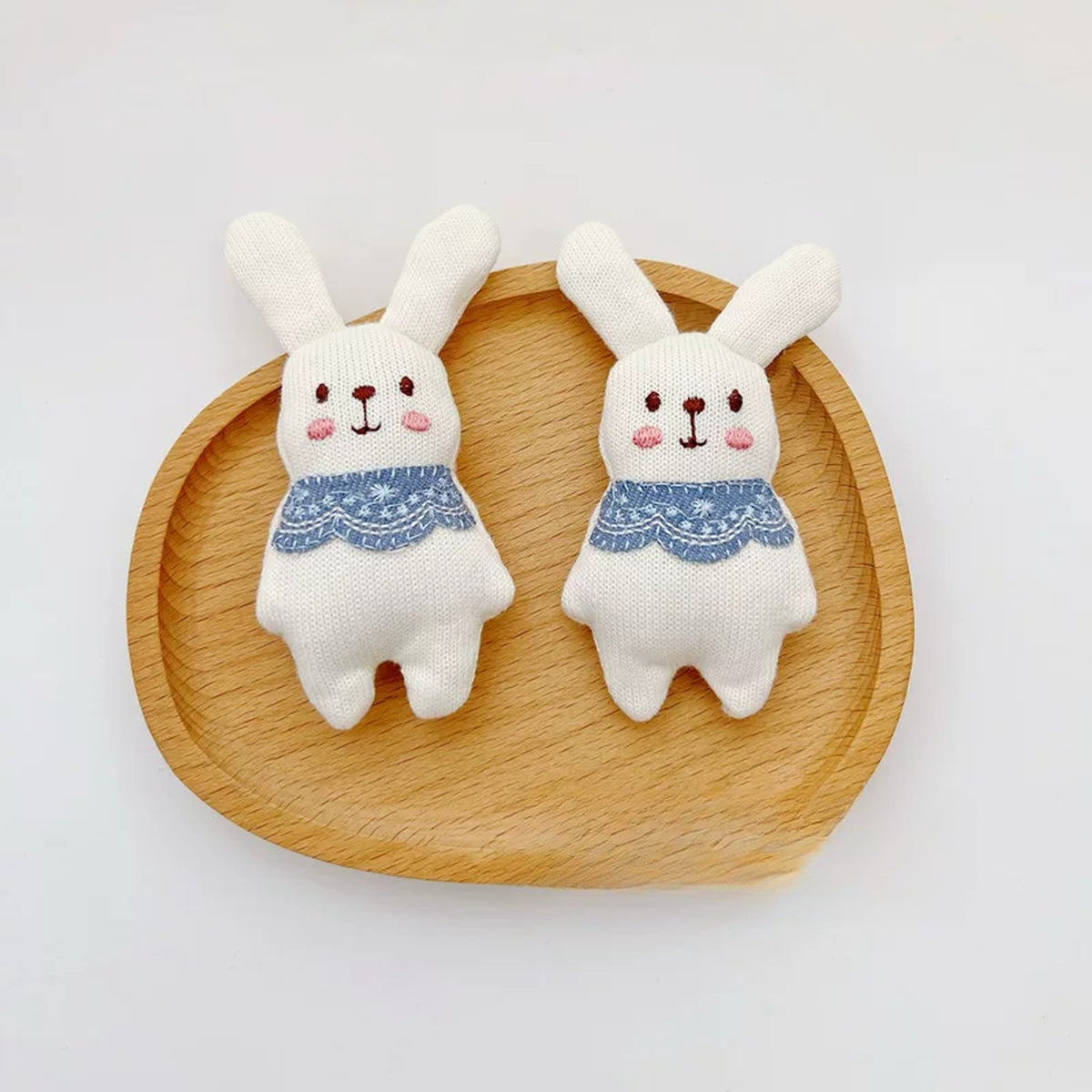 Close-up of two knitted bunny charms with lace collars
