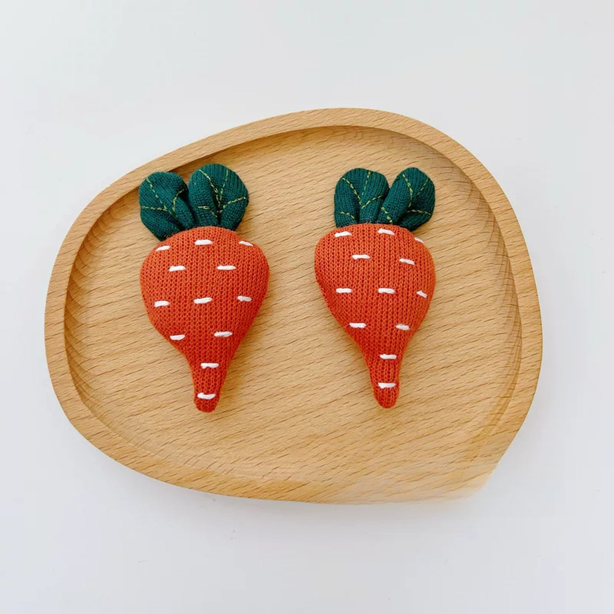 Close-up of two knitted carrot charms with stitched details