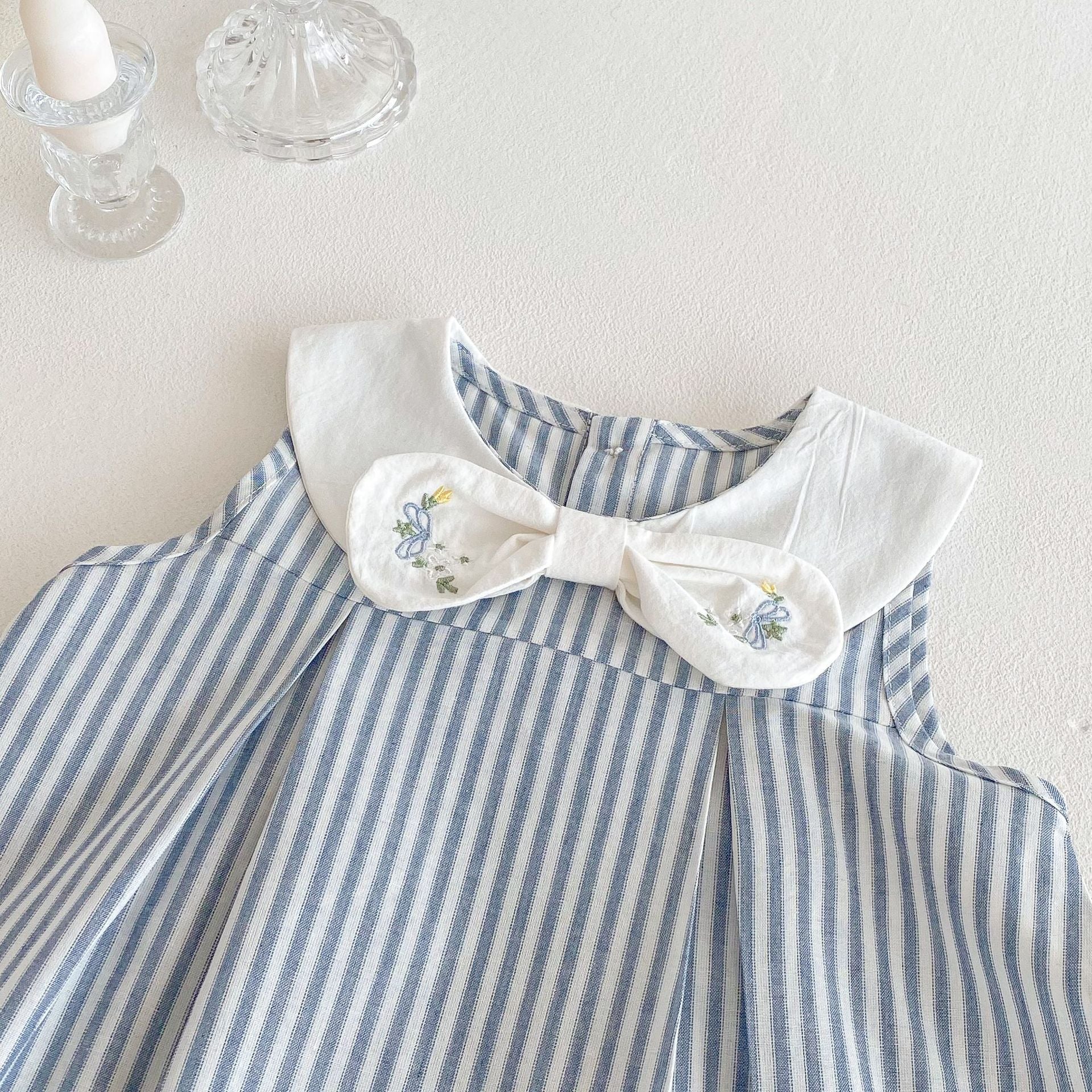 White collar dress with embroidered bow detail on blue striped baby dress