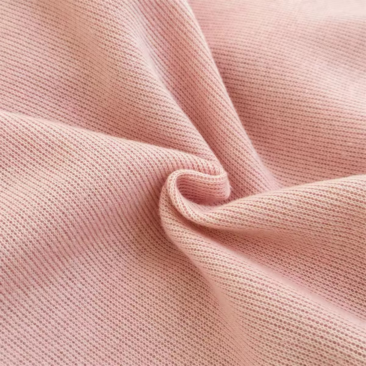 Pink ribbed knit fabric texture close-up for baby jumpsuit
