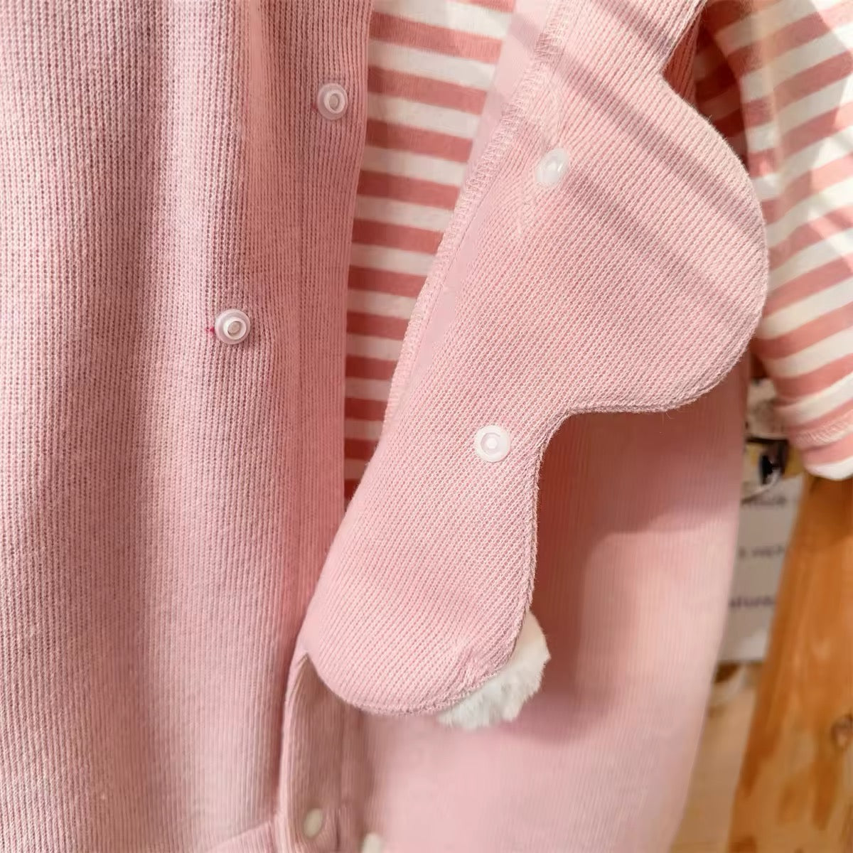 Bunny ear appliqué and snap button placket on pink baby jumpsuit