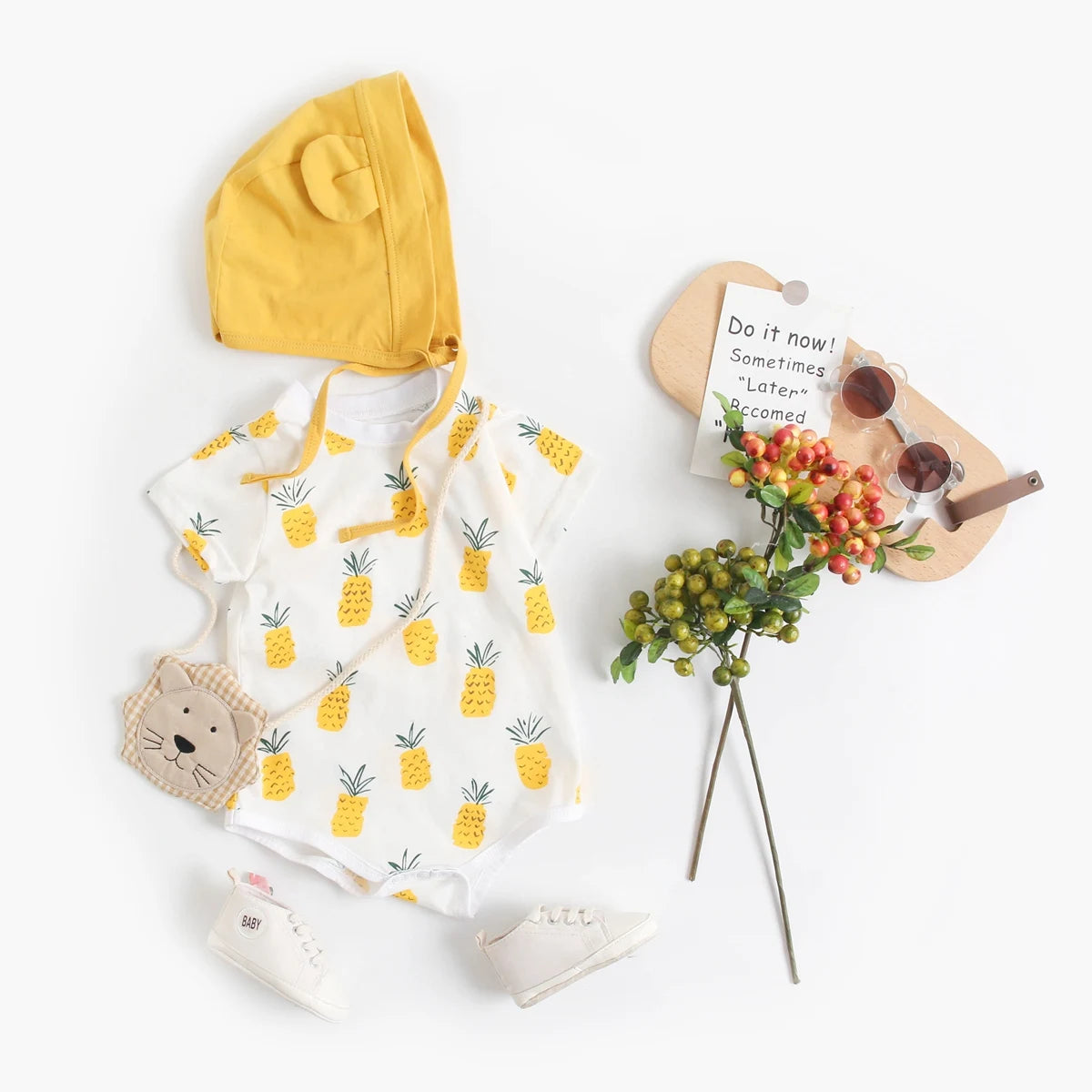 Pineapple print baby bodysuit and bonnet styled with sunglasses and baby shoes