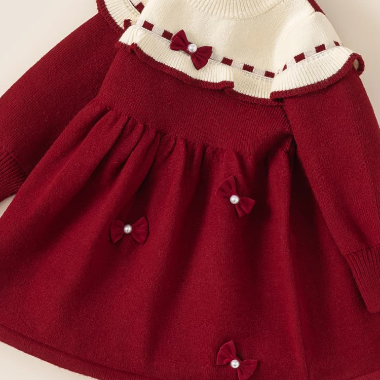 Close-up of the gathered skirt and pearl bows on a red knit toddler dress