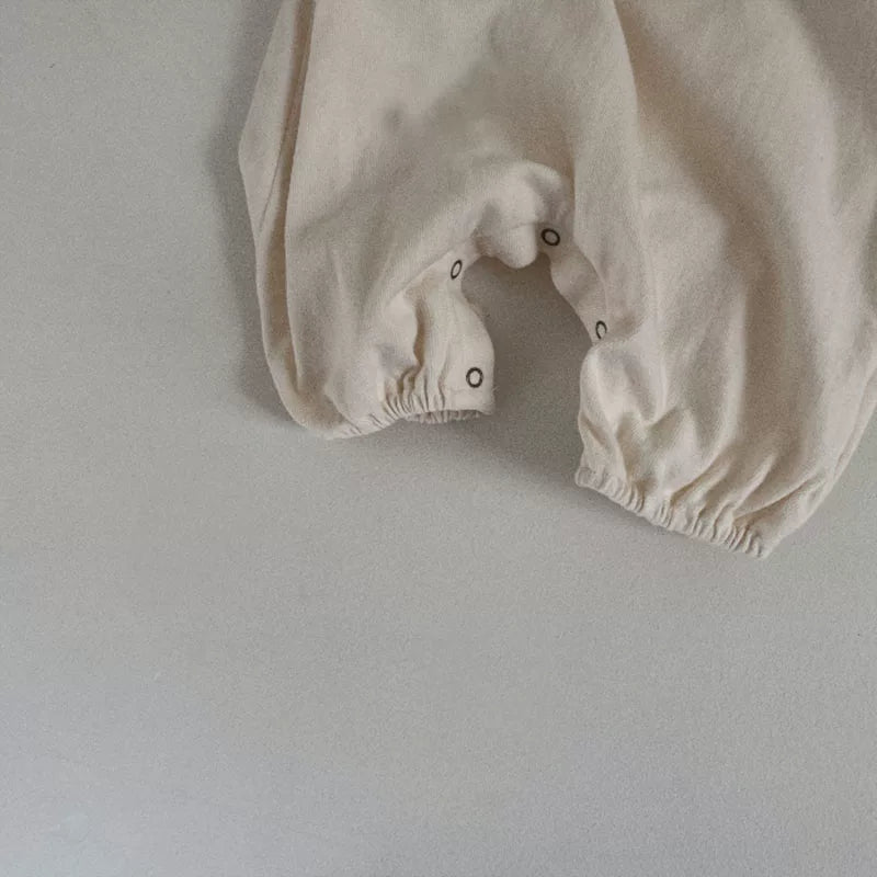 Snap crotch and elastic ankle cuffs on the cream romper