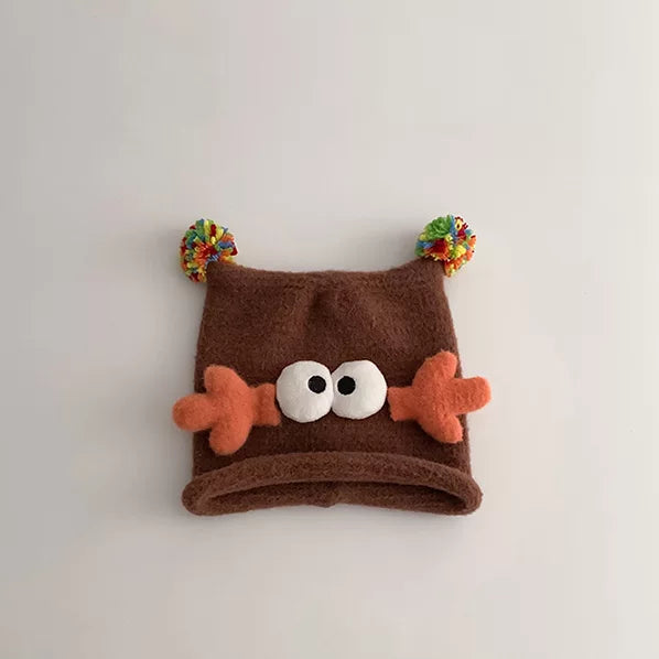 Cocoa brown knit beanie with orange antlers and googly eyes, flat lay