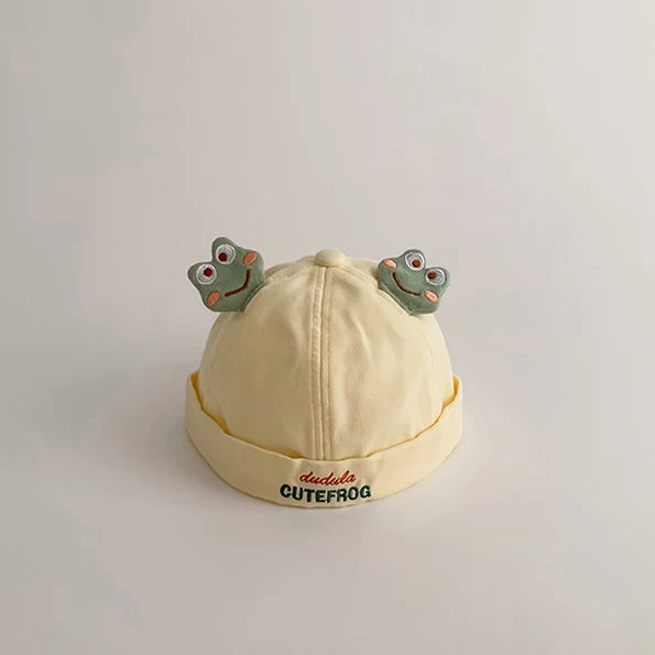 Butter yellow baby beanie with two frog faces and a rolled brim