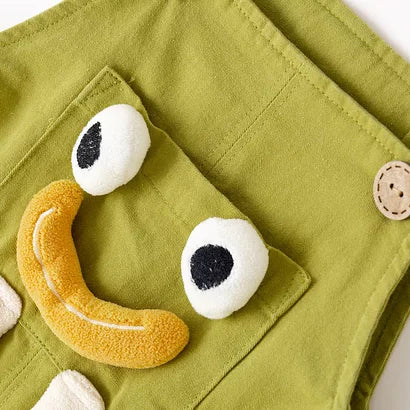 Close-up of plush eyes and smile on green kids dungarees