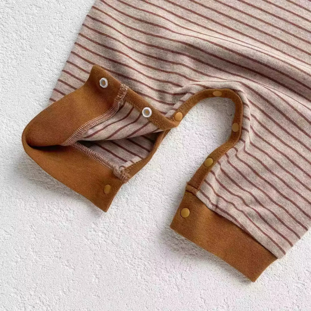 Snap legs and ribbed caramel cuffs on a mocha striped baby romper