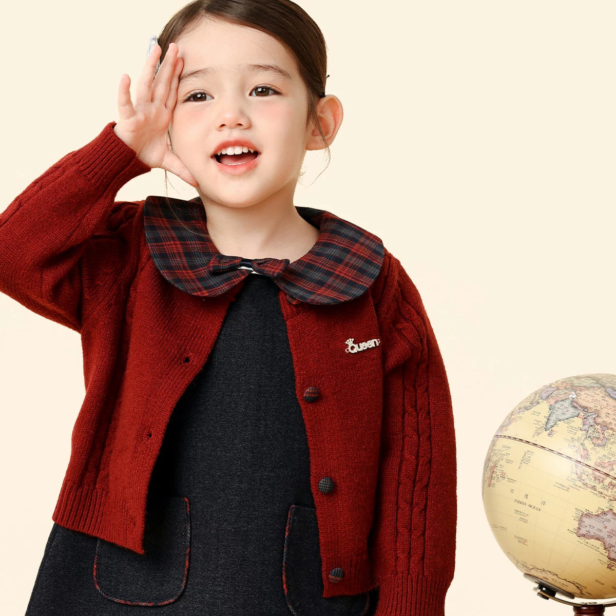 Toddler girl smiling in the burgundy knit cardigan and navy dress set