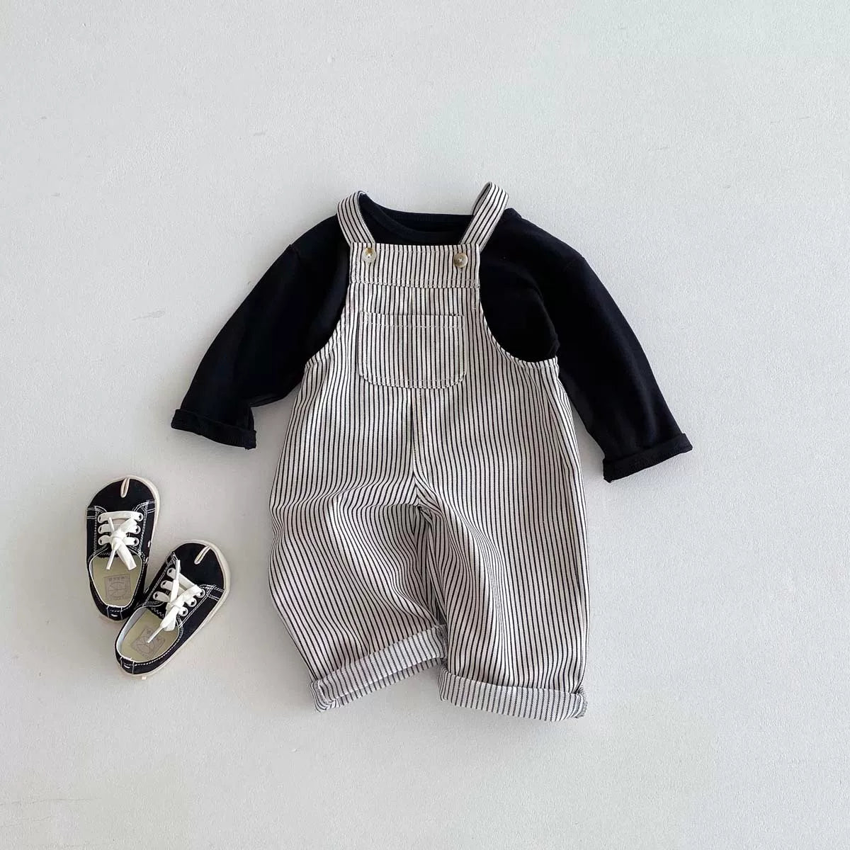 Striped overalls styled with a black tee and sneakers