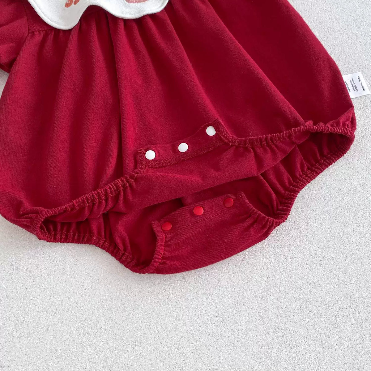 Snap crotch and elastic leg detail on the red baby bodysuit