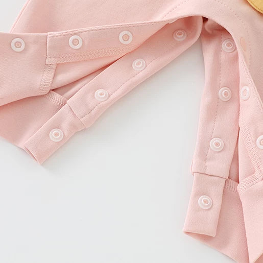 Snap buttons along the legs of the pink romper for easy changes