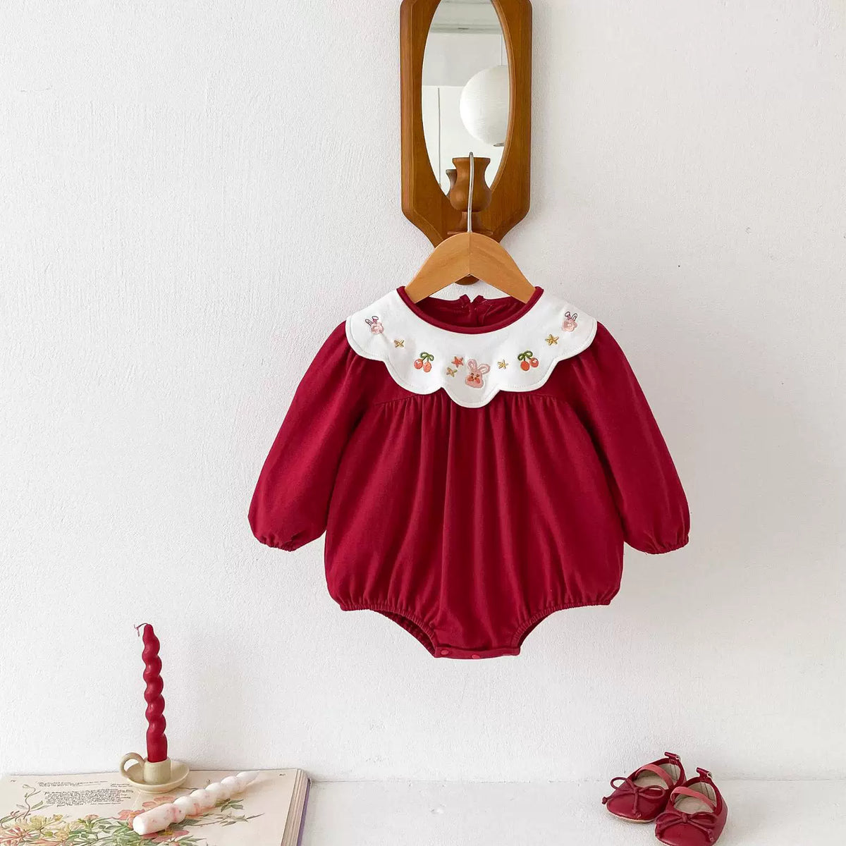 Long-sleeve red bodysuit with embroidered collar on a hanger