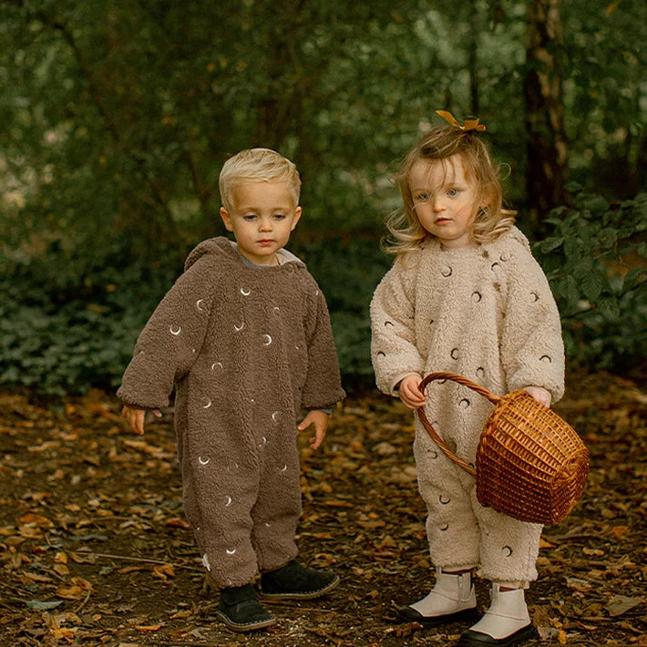 Two toddlers in cocoa and camel moon fleece rompers in autumn leaves