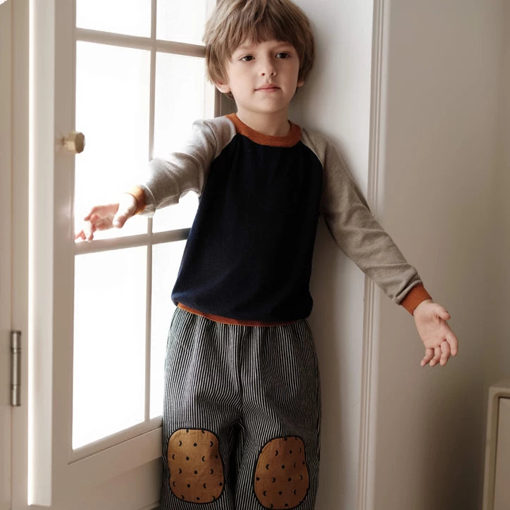 Full-length view of kids striped pants with knee patches by a window
