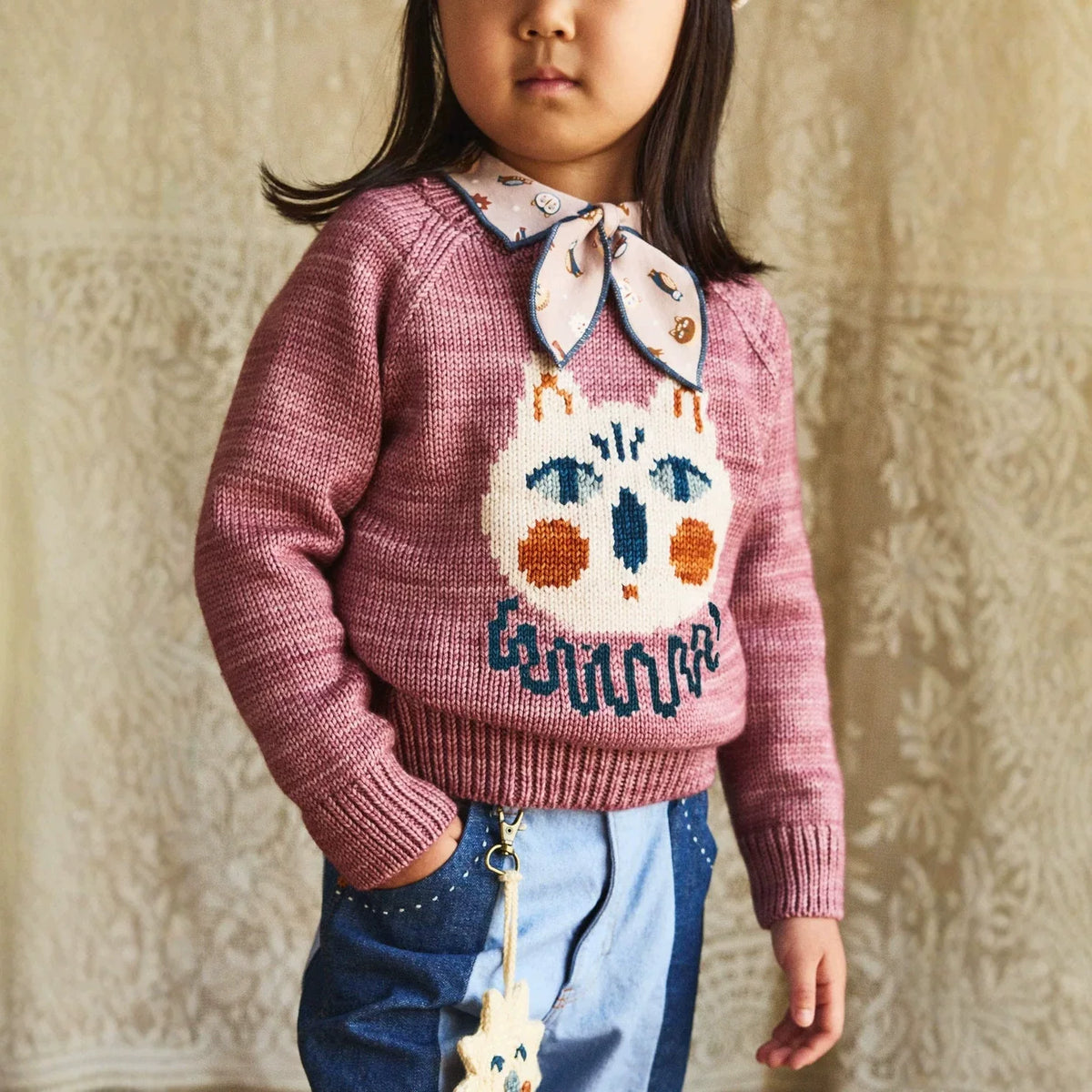 Girl wearing a berry cat sweater with a bow scarf