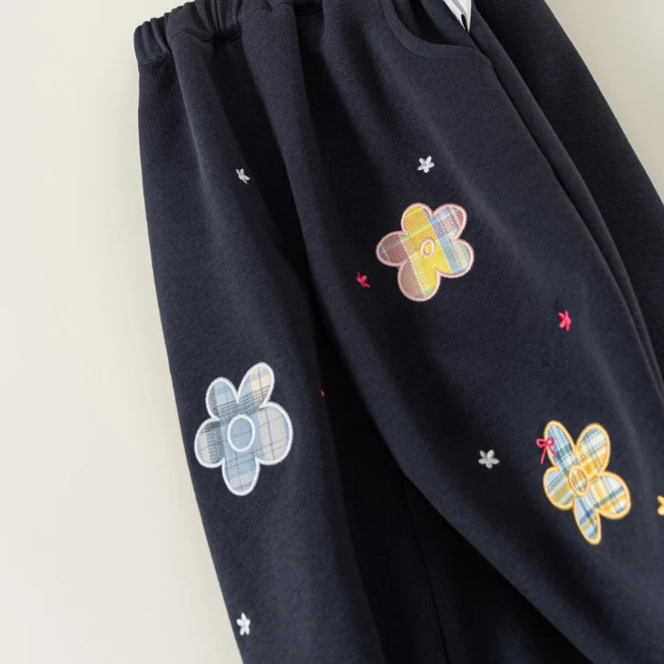Close-up of plaid flower appliqués and tiny embroidered stars on navy pants