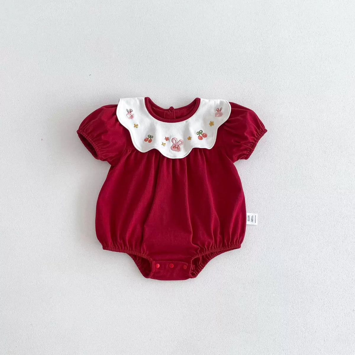 Berry red short puff-sleeve baby bodysuit on a white background