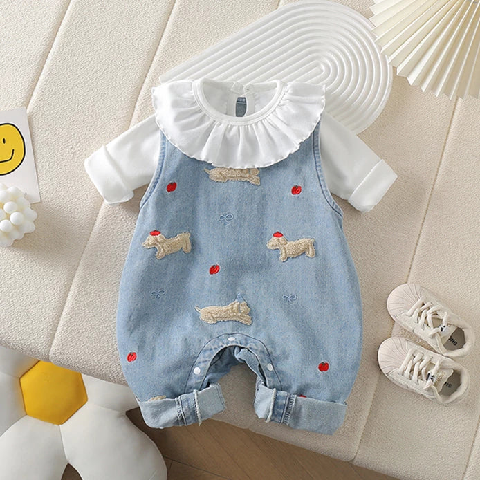 Light denim baby overalls with dachshund appliqués layered over a white ruffle-collar top, flat lay