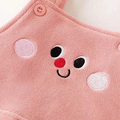 Close-up of the embroidered bunny face and button straps on rose fleece overalls