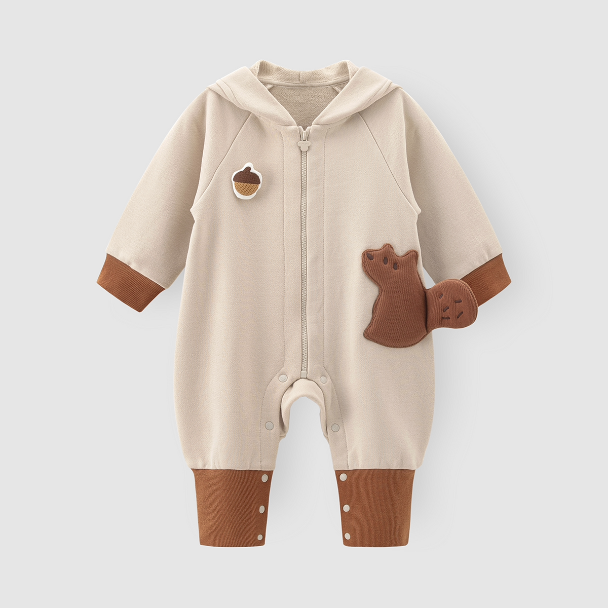 Oatmeal hooded baby romper with squirrel appliqué and rust ribbed cuffs, flat lay