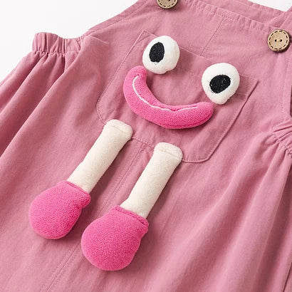 Pink overalls bib with plush smiley face and button straps