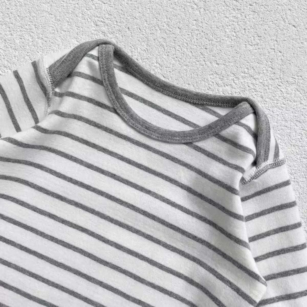 Close-up of the envelope neckline on a grey striped baby romper