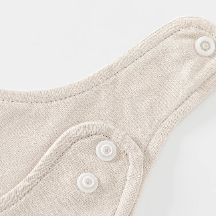 Snap-button shoulder strap detail on almond baby overalls